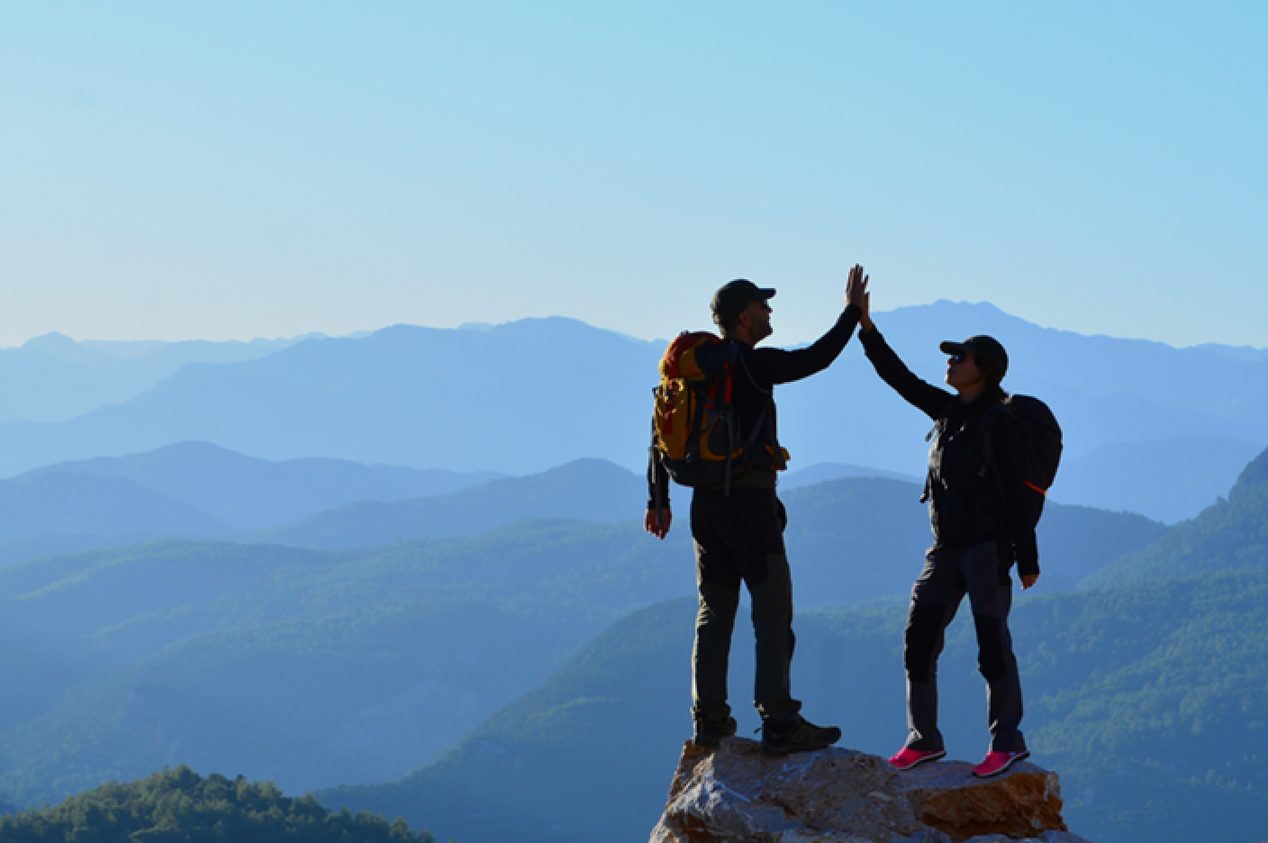 山頂でハイタッチする２人の登山者